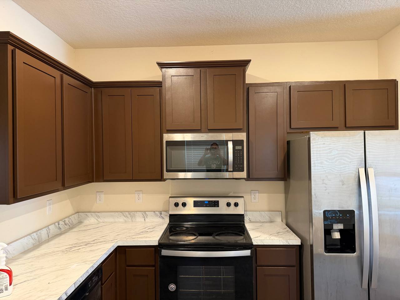 After: kitchen cabinets refinished in an even warm brown, with clean edges against the ceiling and countertop.