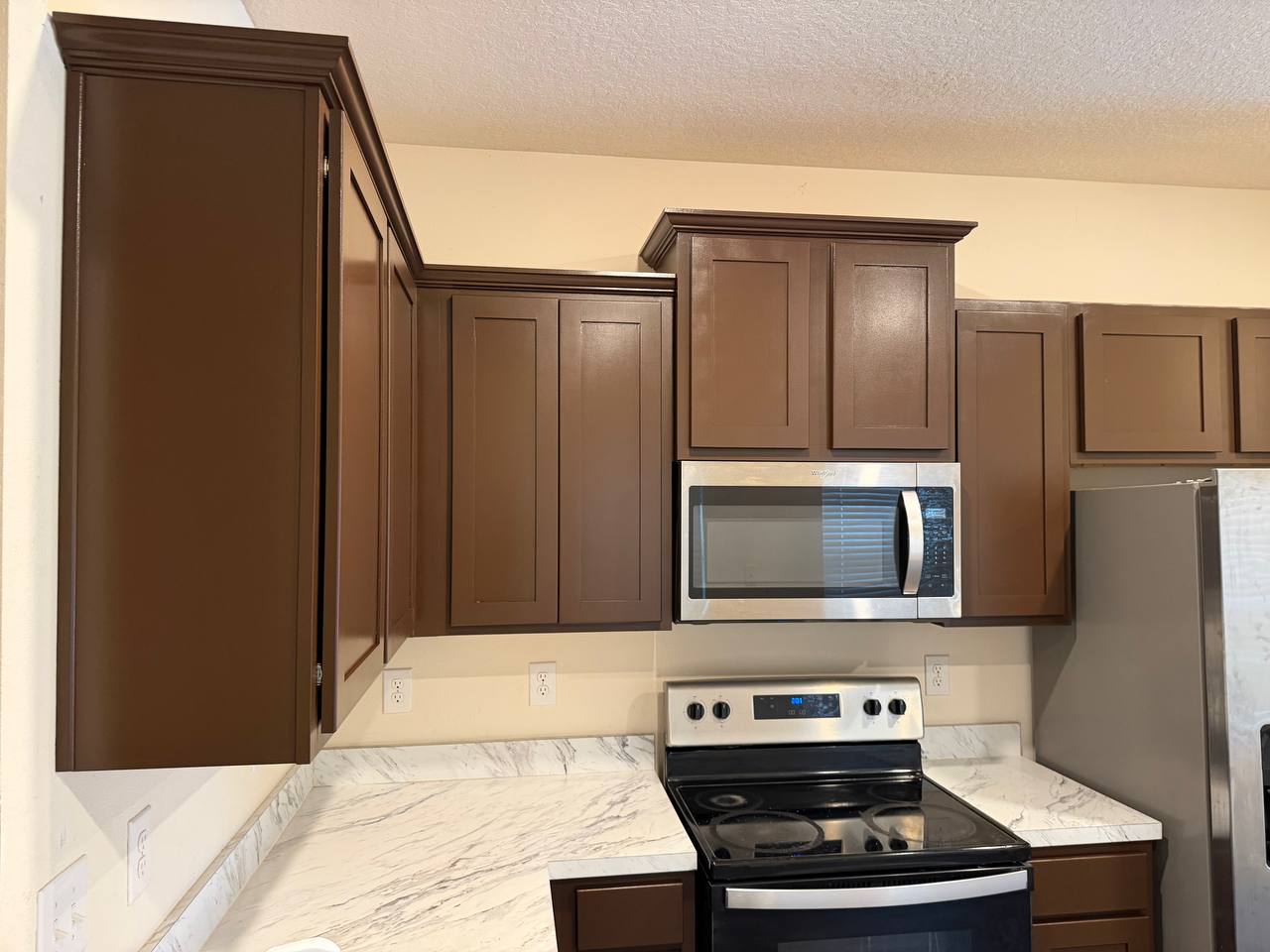 After: refinished upper cabinets in an even warm brown with a clean crown moulding line.