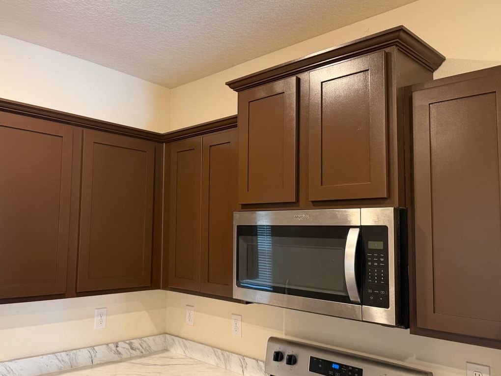 After: the same kitchen corner with cabinets refinished in an even, rich warm brown.