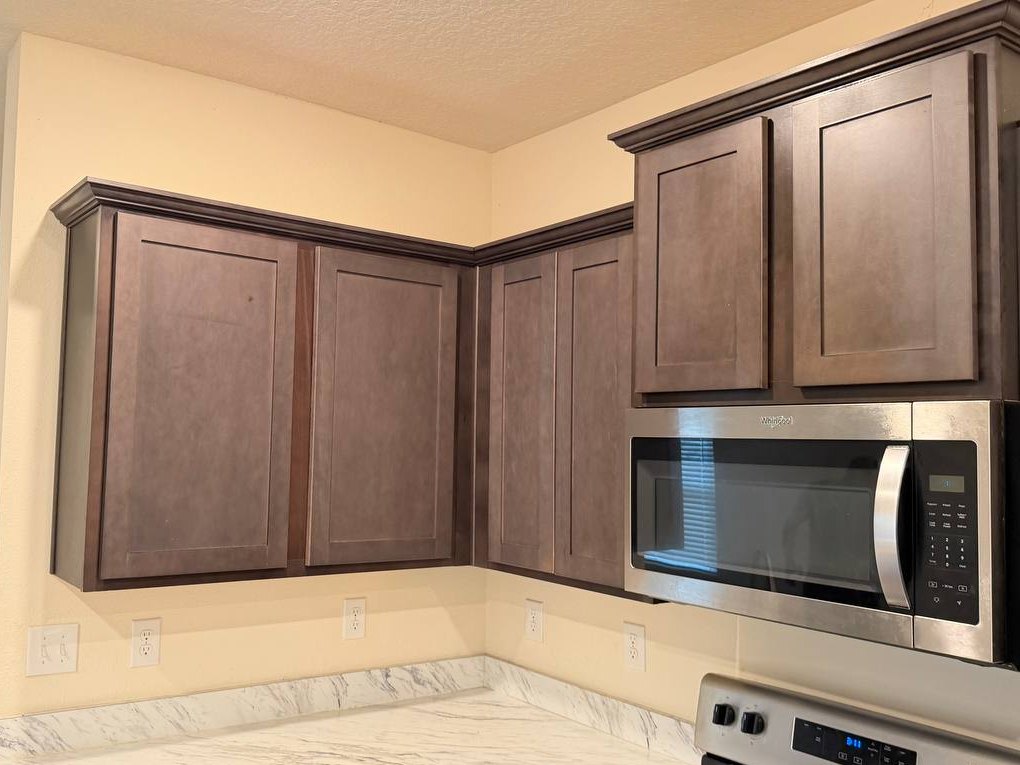 Before: kitchen corner wall cabinets in a dull, faded grey-brown.