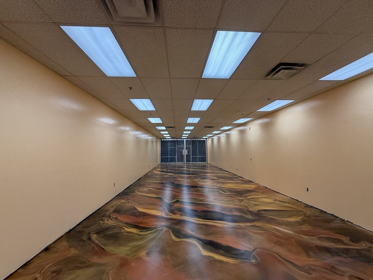 Long commercial corridor with rebuilt and freshly repainted walls, recessed ceiling lighting and a decorative marbled epoxy floor.